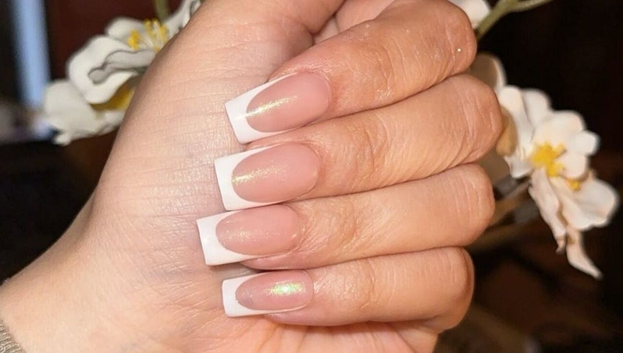 French manicured hand from Klaw Cartel in Birmingham, England, GB against a floral background.