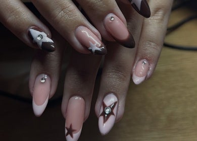 Elegant nail art with star designs at Klaw Cartel, Birmingham, England, GB on a wooden surface.