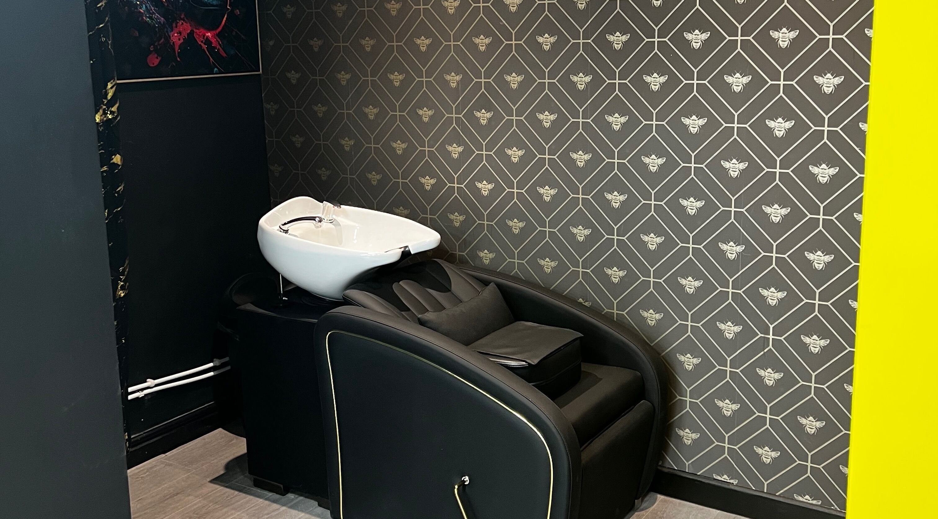Elegant wash station at MMS Mattys Mane Studio, Stockport, England, GB features plush seating and bee-patterned wall.