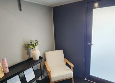 Relaxing corner at Nail Nook, Cooranbong, New South Wales, AU with chair, table, water, and flowers.