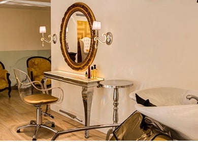 Elegante salón interior de Francisco Peluqueros en Palma, Illes Balears, ES, con espejo decorativo y sillas doradas.