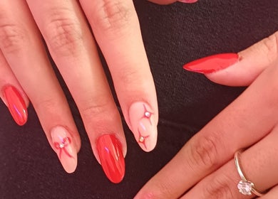 Elegante rote und rosa Nageldesigns mit Schmucksteinen bei NailBar Visp, Visp, Wallis, CH.