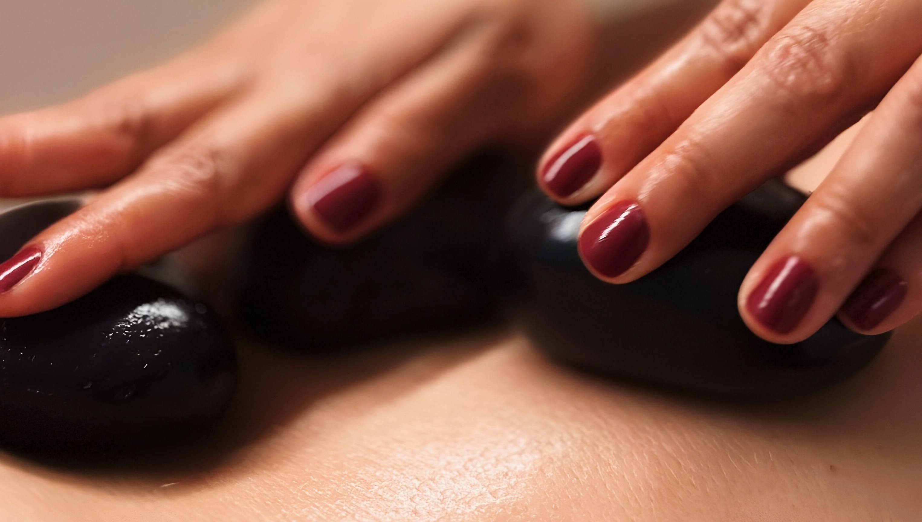 Pedras quentes em massagem no Positive Hands, Quarteira, Faro, PT, criando uma experiência relaxante.