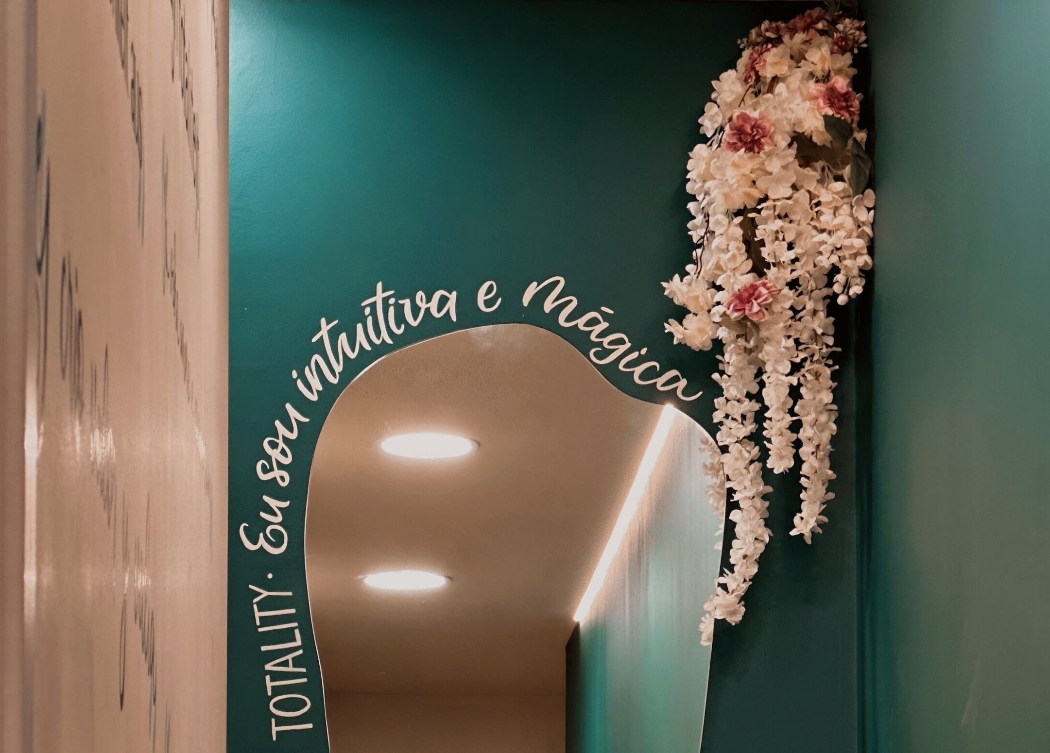 Espelho decorado com flores brancas e texto na parede em Positive Hands, Quarteira, Faro, PT.