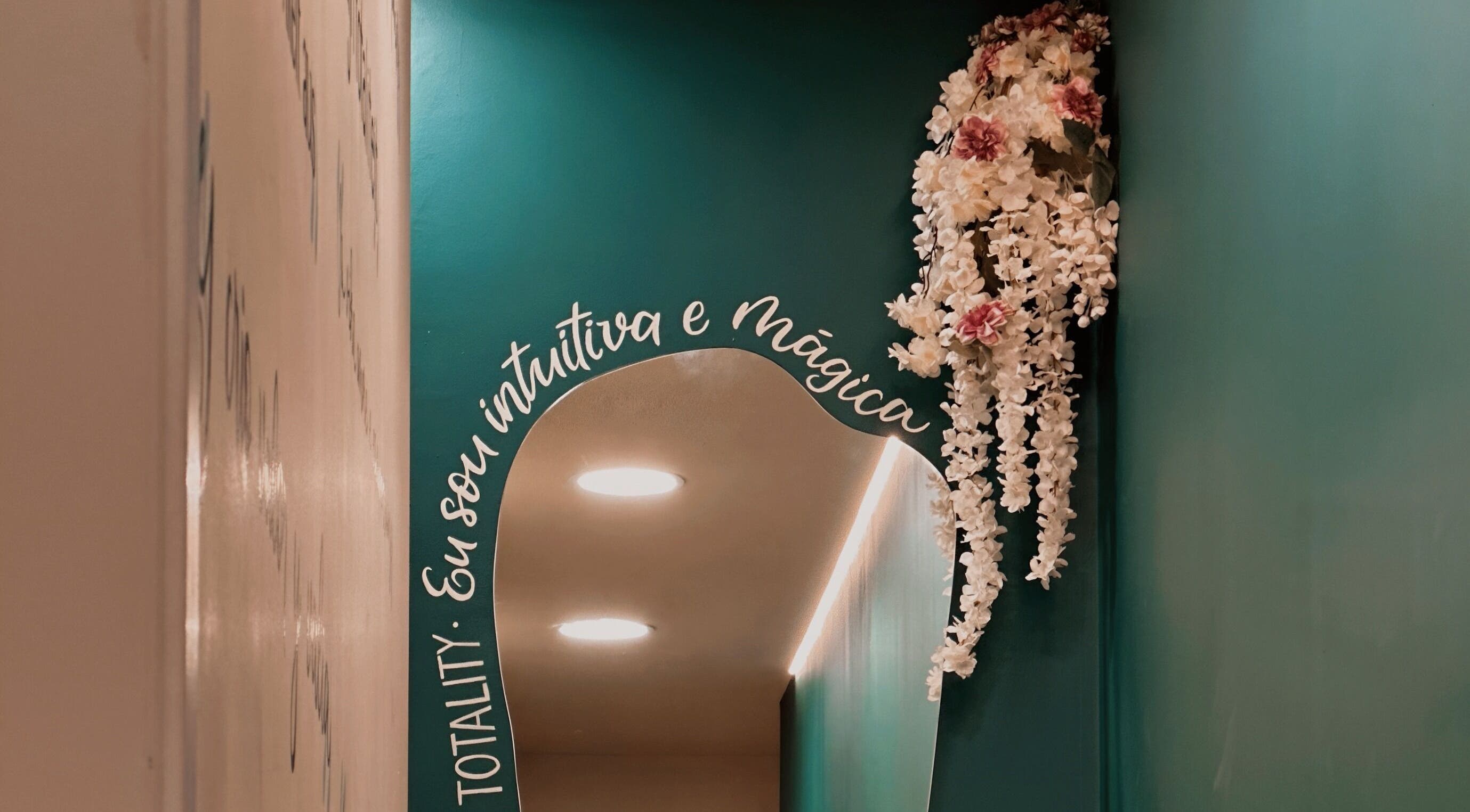 Espelho decorado com flores brancas e texto na parede em Positive Hands, Quarteira, Faro, PT.