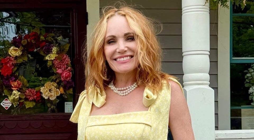 Smiling person in front of Rusted Daisy Salon & Boutique, Flowery Branch, Georgia, US, with floral arrangement.
