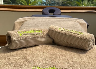 Luxurious massage table at Pasithea Massage by Appointment, Ventnor, England, GB, with cozy towels and sunlight.
