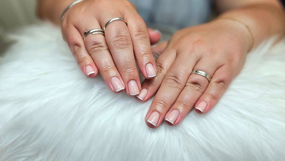 Classic French manicure at Dark Envy Nails in Swaffham, England, GB on a plush white surface.