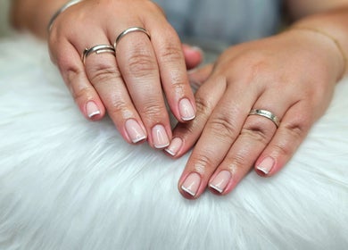 Classic French manicure at Dark Envy Nails in Swaffham, England, GB on a plush white surface.