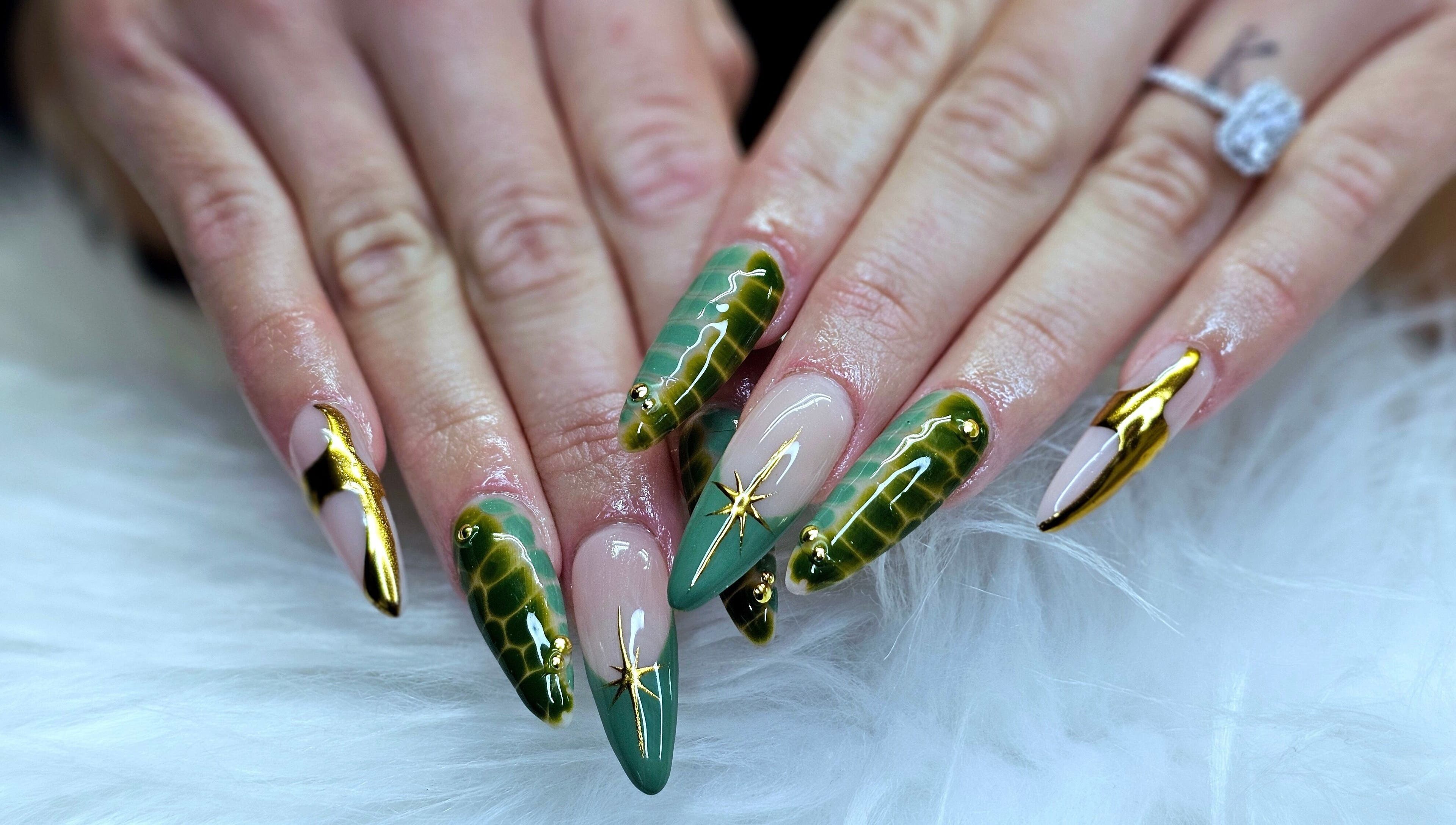 Stunning green and gold nail art by Dark Envy Nails in Swaffham, England, GB on a fluffy white surface.