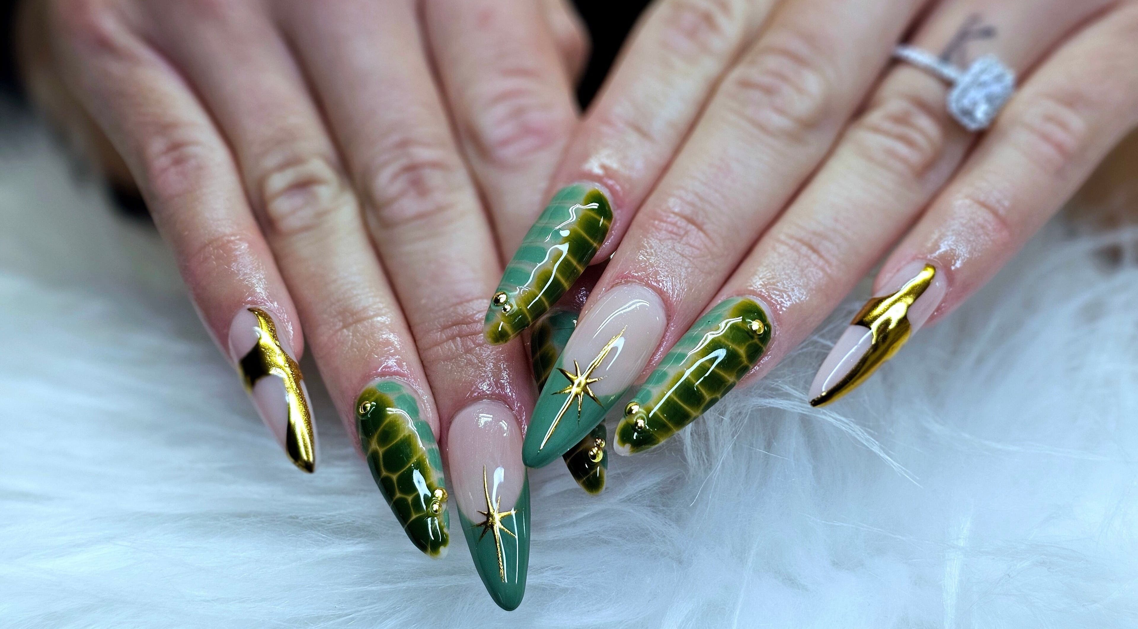 Stunning green and gold nail art by Dark Envy Nails in Swaffham, England, GB on a fluffy white surface.