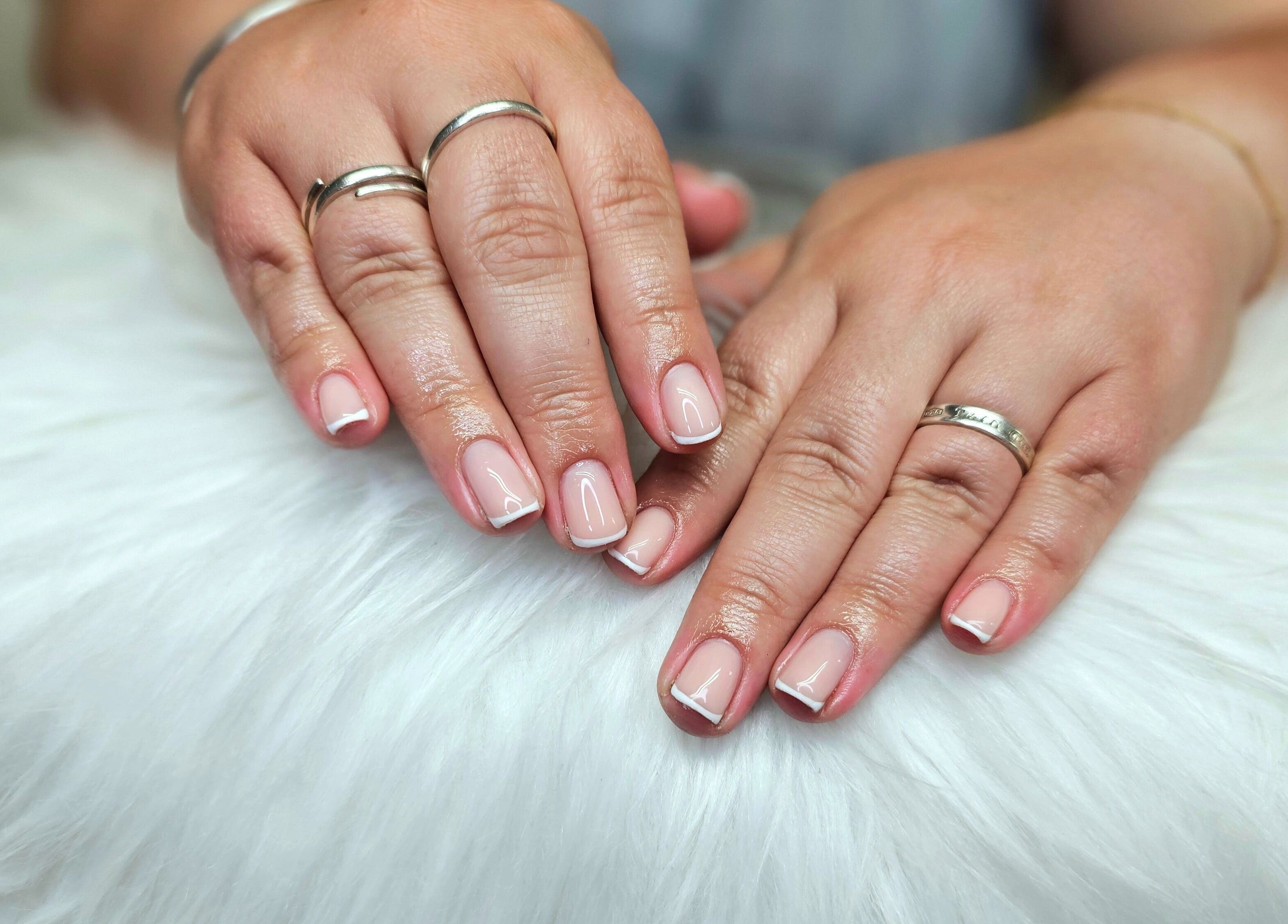 Elegant French manicure at Dark Envy Nails, Swaffham, England, GB. Perfectly polished nails with stylish rings.