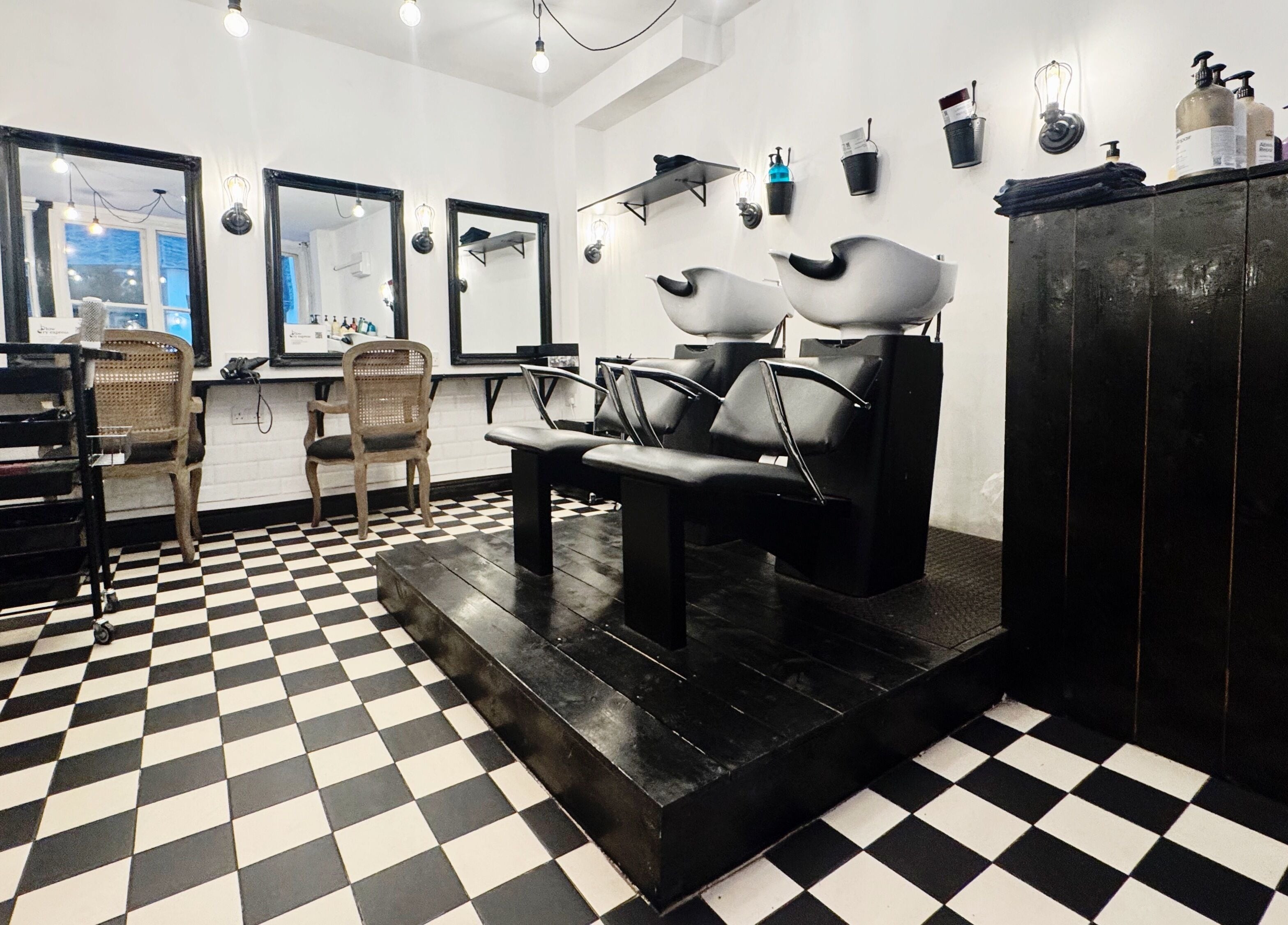 Elegant salon interior at Blow Dry Express - Monument in London, United Kingdom, GB with stylish chairs and mirrors.