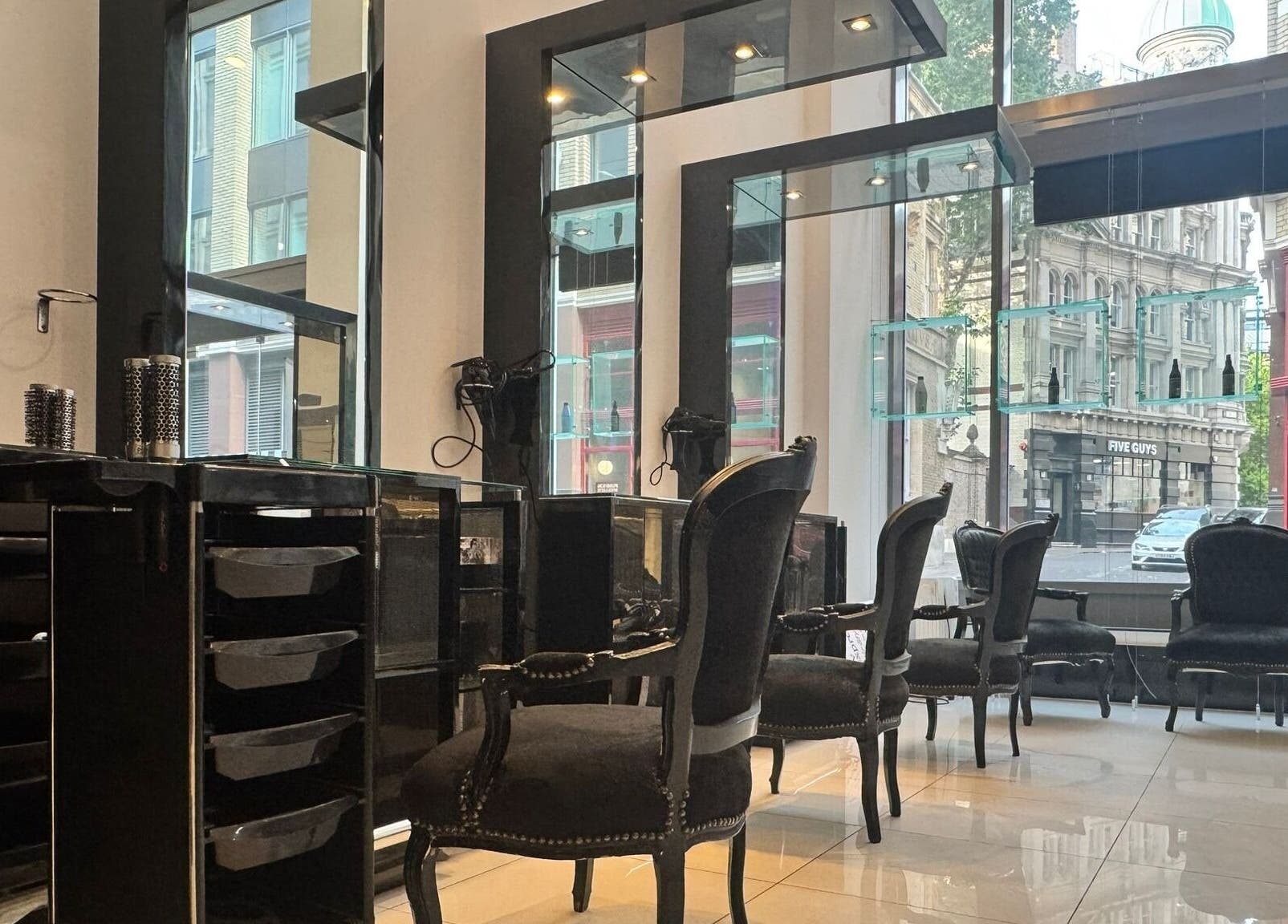 Stylish interior of Blow Dry Express - St Pauls, London, United Kingdom, GB, showcasing elegant black chairs and mirrors.