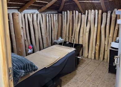 Cozy massage room at Tiara's Beauty Spa in Cape Town, Western Cape, ZA with rustic wooden decor and a massage table.
