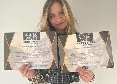 Woman proudly displaying certificates at Elegance Permanent Makeup, Nottingham, England, GB.