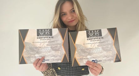 Woman proudly displaying certificates at Elegance Permanent Makeup, Nottingham, England, GB.