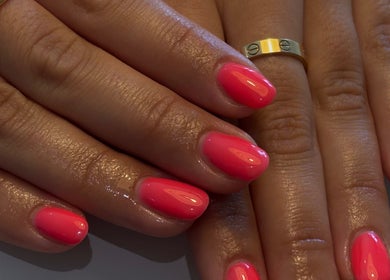 Vibrant pink manicure at AmiRoseBeauté, Barrington, England, GB showcasing elegant nail art and gold rings.