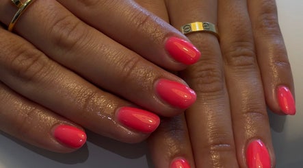 Vibrant pink manicure at AmiRoseBeauté, Barrington, England, GB showcasing elegant nail art and gold rings.