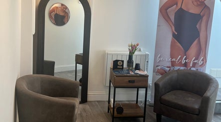 Cozy seating area at Niymimi Aesthetics, London, England, GB showcasing modern decor and promotional banner.