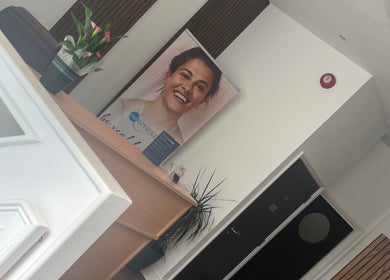 Reception area at Niymimi Aesthetics in London, England, GB featuring a smiling poster and elegant decor.