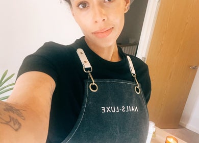Nail technician in apron at Lola Nail Aesthetics, Chadderton, England. Modern ambiance and service excellence.