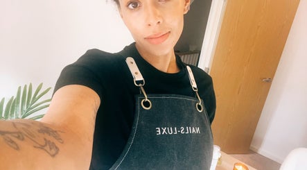 Nail technician in apron at Lola Nail Aesthetics, Chadderton, England. Modern ambiance and service excellence.