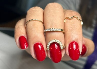 Uñas esmaltadas en rojo vibrante con anillos en Takesshy Beauty, Madrid, Comunidad De Madrid, ES.