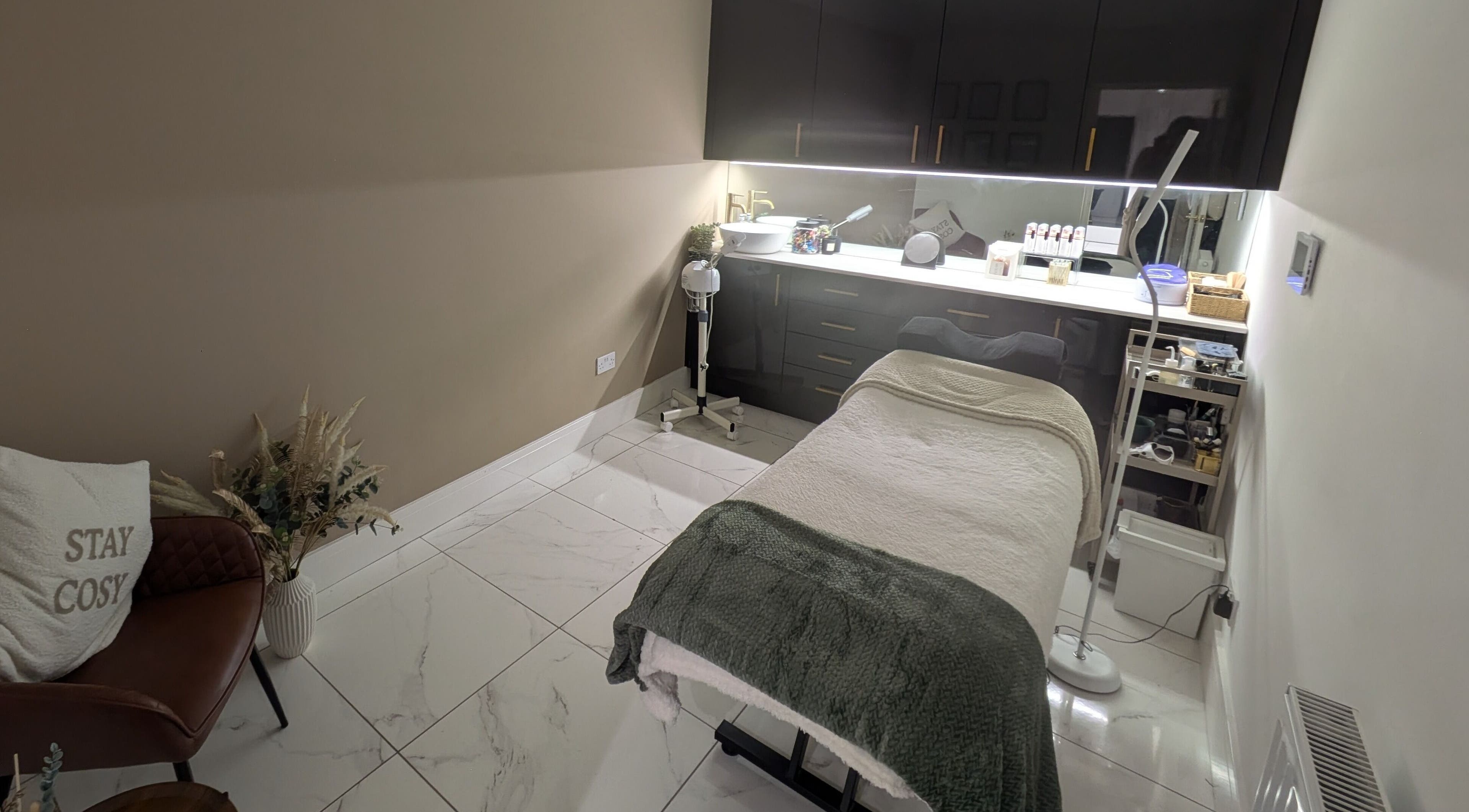 Relaxing treatment room at Sanctuary Beauty & Aesthetics, Hyde, England, GB. Cozy chair and treatment bed.