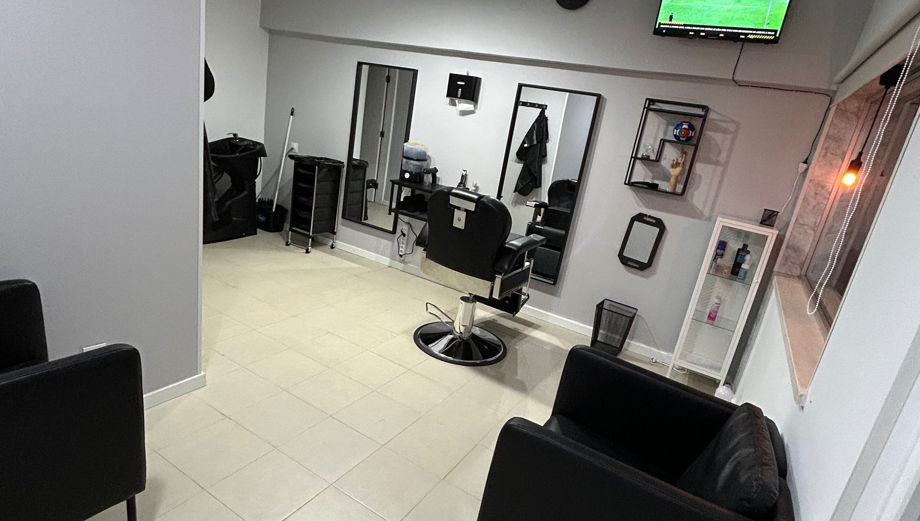 Espaço interior de Bronk's Barbearia em Fernão Ferro, Setúbal, PT com cadeira de barbeiro e espelhos modernos.