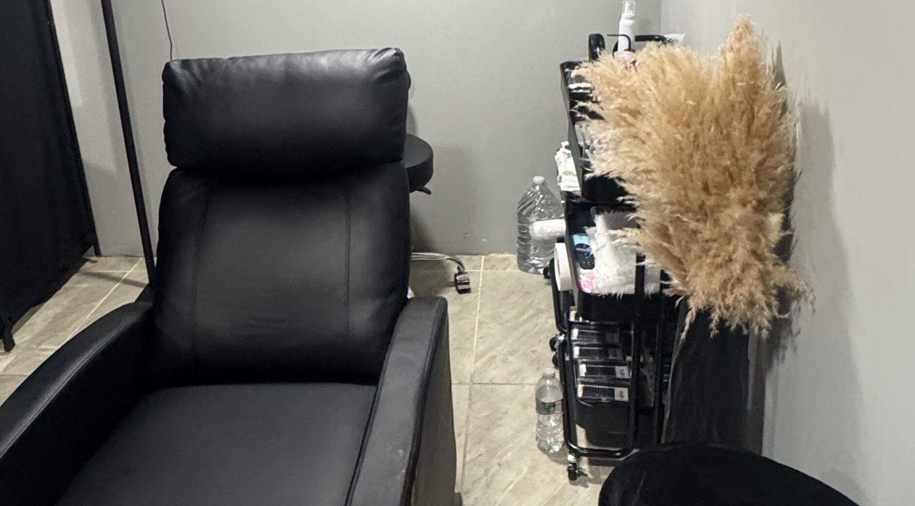 Sala de belleza en Darg Lashes, Rahway, New Jersey, US, con cómoda silla negra y estante de suministros.