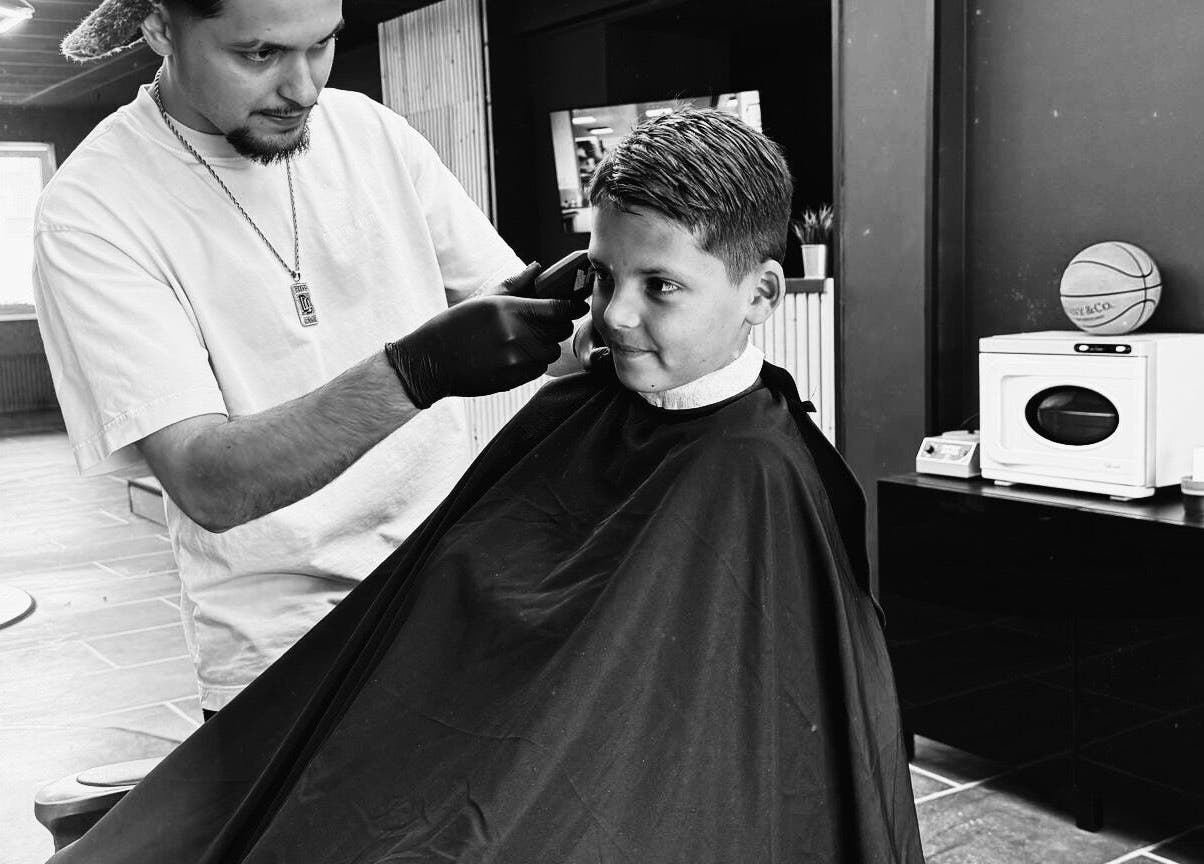 Kapper bij Shyycutsz in Beek, Limburg knipt het haar van een jongen met zorg.