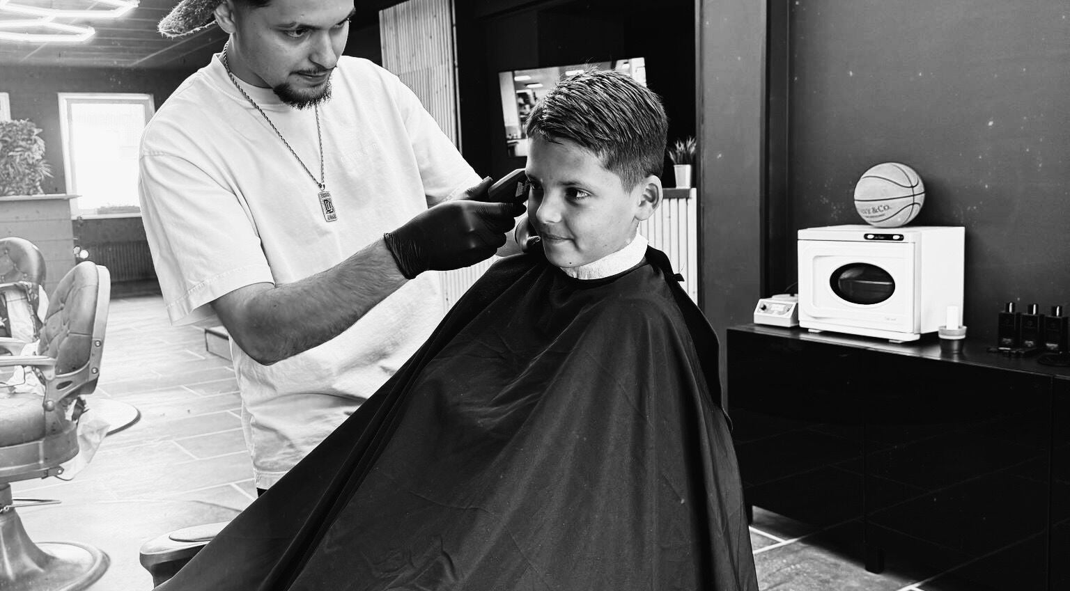 Kapper bij Shyycutsz in Beek, Limburg knipt het haar van een jongen met zorg.