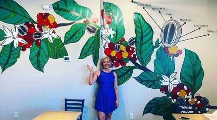 A person in blue dress waves in front of a vibrant floral mural at Barbee Studio, Bowling Green, Kentucky, US.