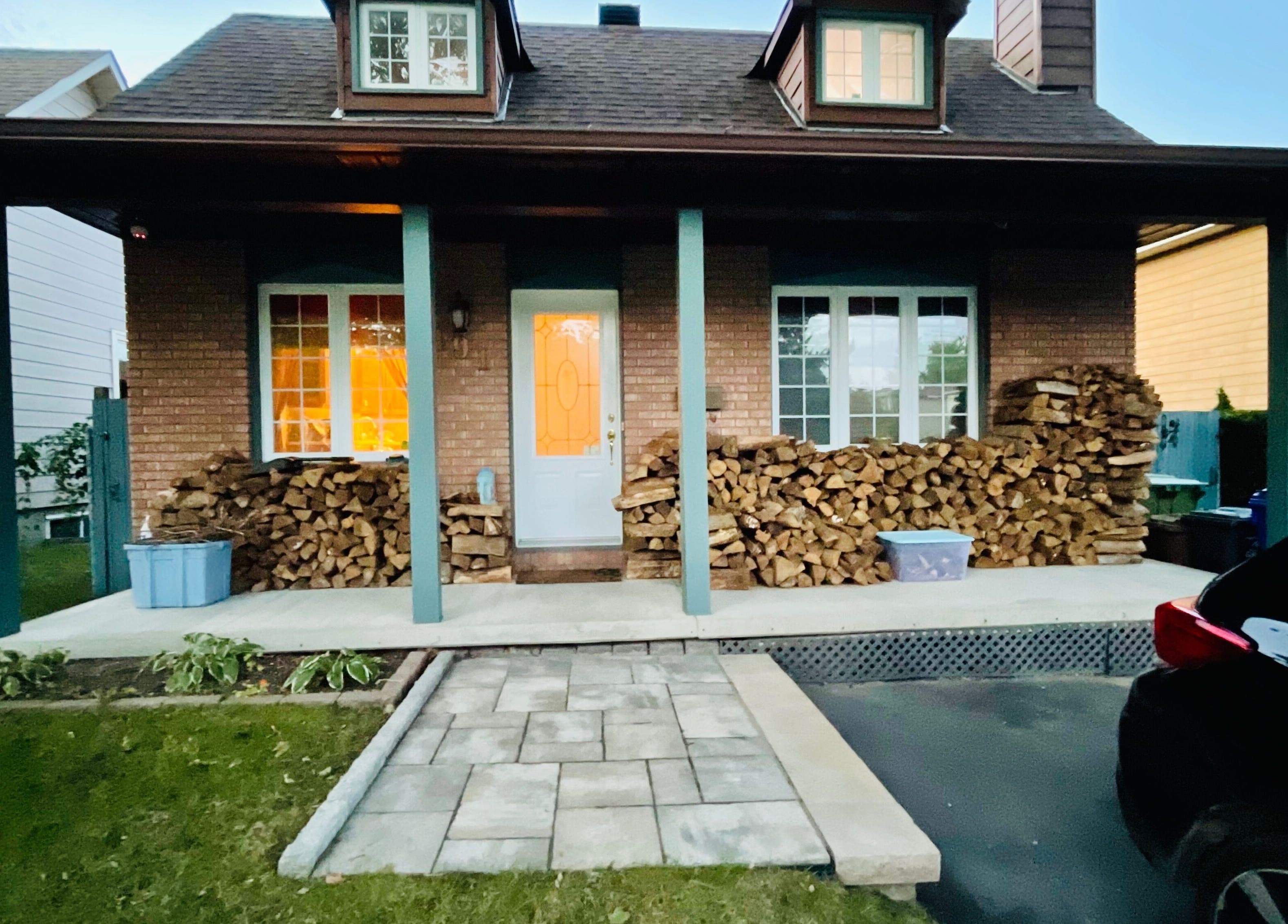 Charming front porch at Radiance Sculpt & Flow Studio in Gatineau, Québec, CA with stacked firewood.