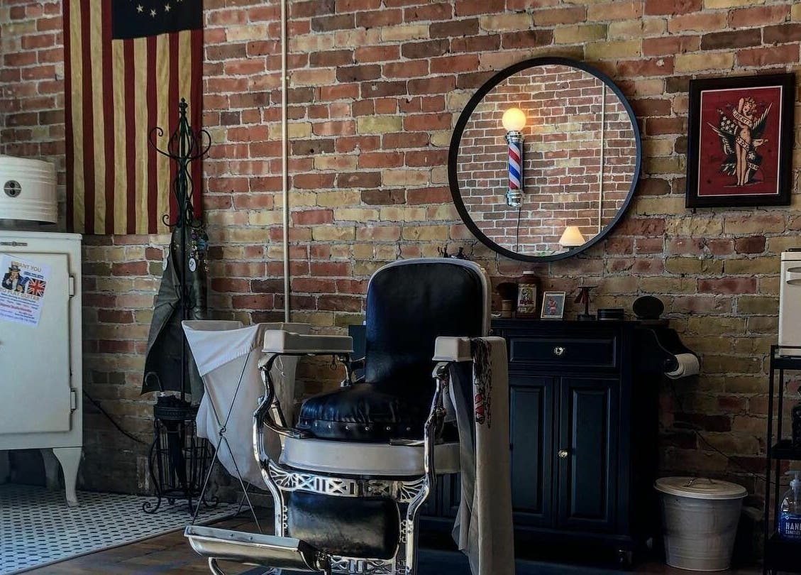 Charming vintage barber chair at The Man Barber LLC, Provo, Utah, US set against an exposed brick wall.