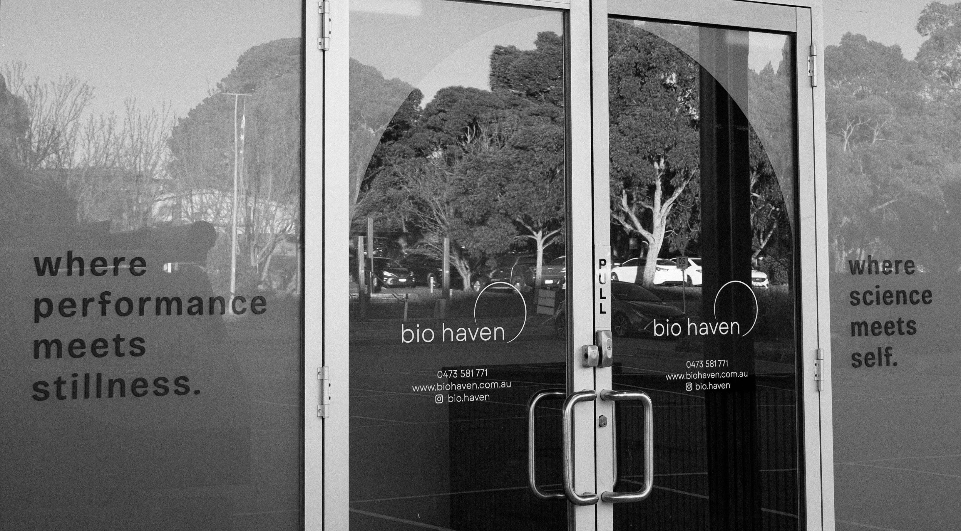 Entrance of Bio Haven in Somerville, Victoria, AU, featuring glass doors with reflections and motivational text.