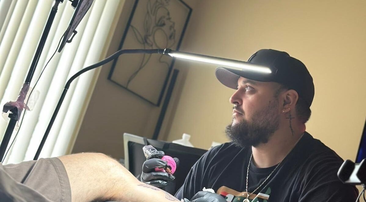 Tattoo artist at Arnidez in Auburn, Washington, US, creating detailed artwork under focused lighting.