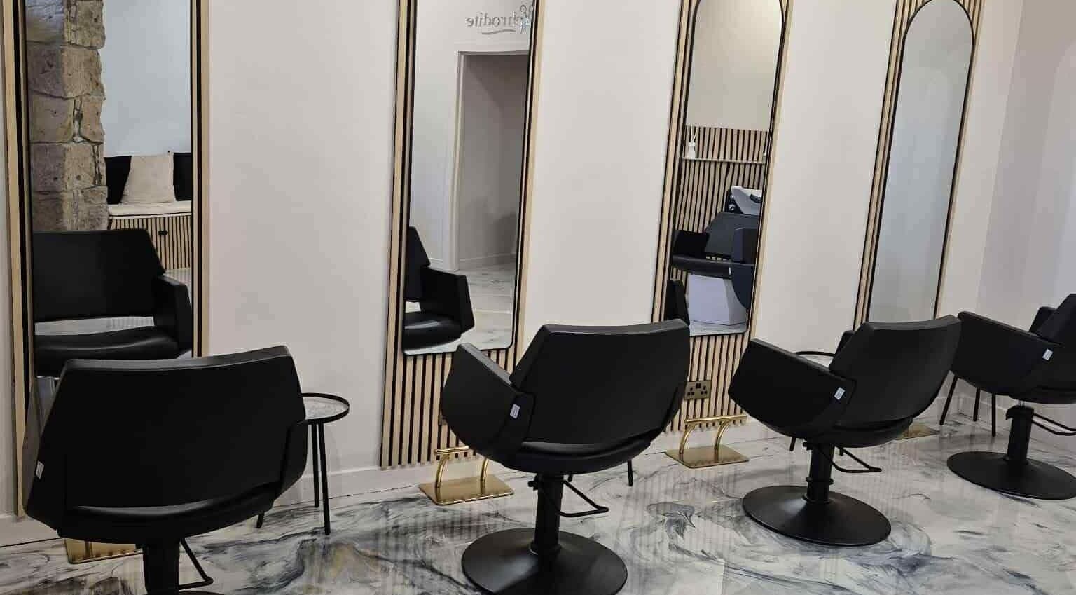 Chic salon interior at Aphrodite in Stirling, Scotland, GB, features sleek black chairs and stylish mirrors.