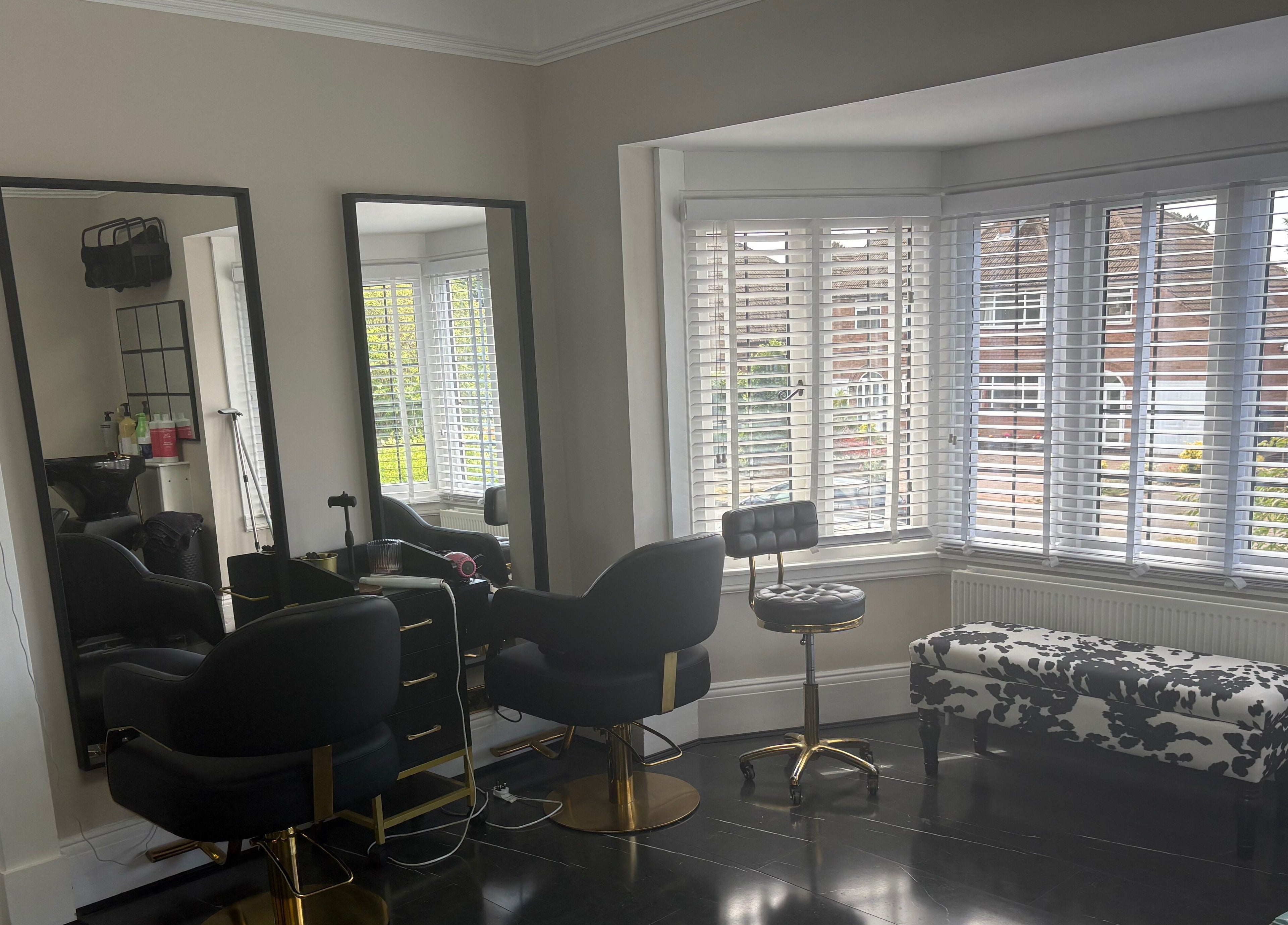 Elegant interior of Hair by Hannah salon in Bentley Heath, England, GB with stylish chairs and large mirrors.