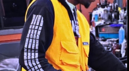 Barber in yellow vest at Faded Barbershop, Detroit, Michigan, US, focusing on a haircut.