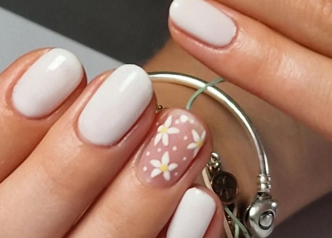 Elegant daisy nail art at Nail Divas, Newport, Wales, GB, featuring white nails with floral accents.