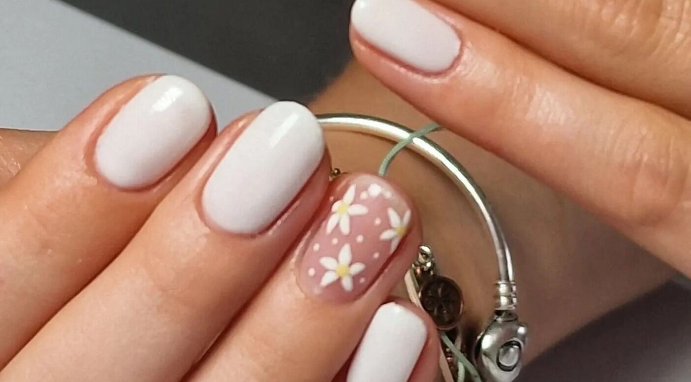 Elegant daisy nail art at Nail Divas, Newport, Wales, GB, featuring white nails with floral accents.