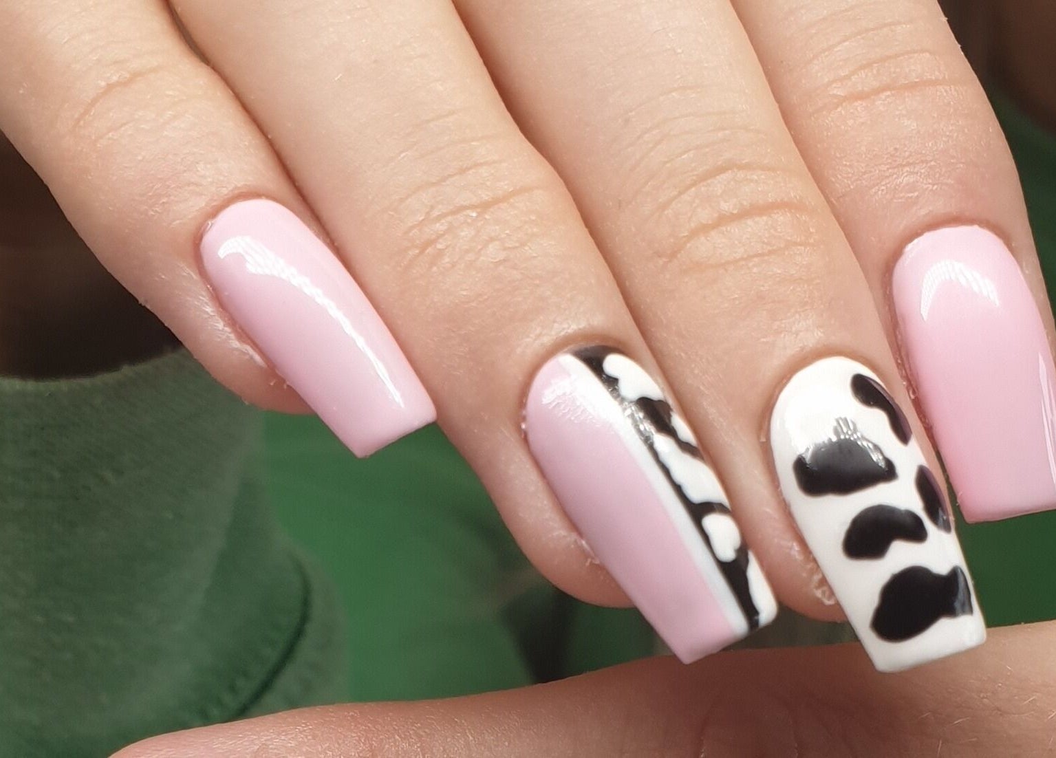 Pink and cow-print nails at Nail Divas in Newport, Wales, GB showcase trendy, creative nail art designs.