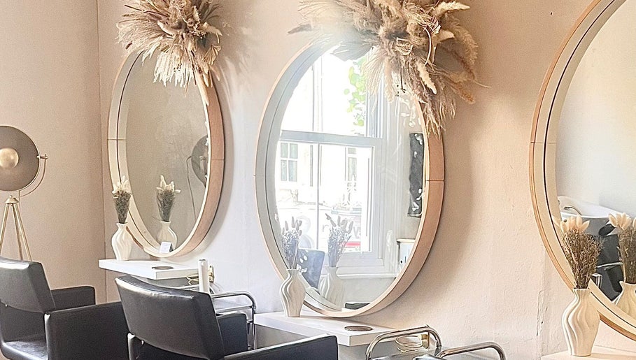 Chic salon interior at Studio H Aesthetics, Barbers & Hair, Norwich, England, featuring round mirrors and decor.