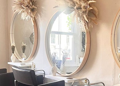 Chic salon interior at Studio H Aesthetics, Barbers & Hair, Norwich, England, featuring round mirrors and decor.