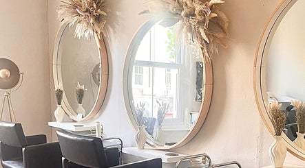 Chic salon interior at Studio H Aesthetics, Barbers & Hair, Norwich, England, featuring round mirrors and decor.