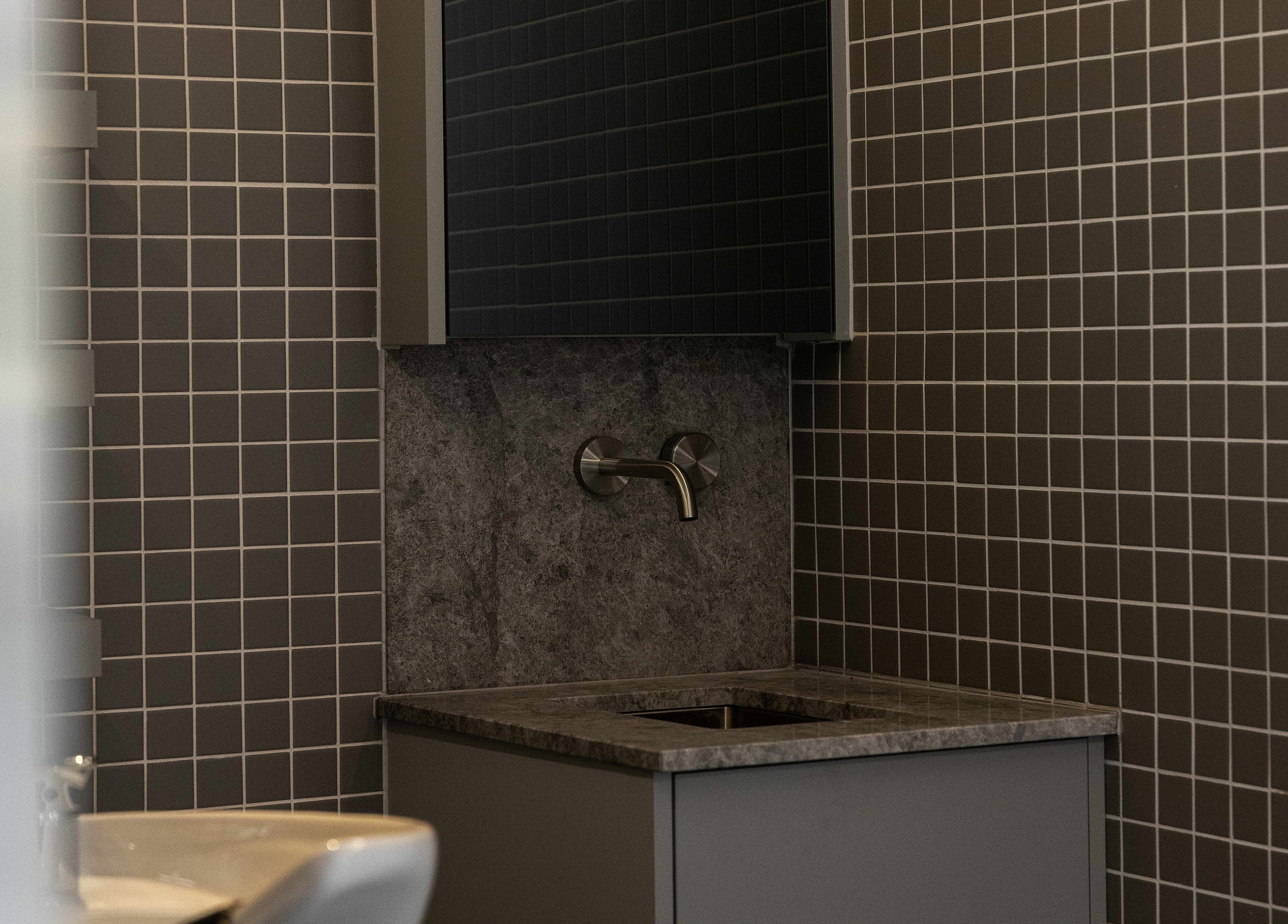 Elegant washbasin area at Alkami in Belconnen, Australian Capital Territory, AU featuring tiled walls.