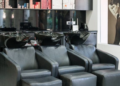 Área de lavado de cabello en Salon Bruno, Las Terrenas, Samaná, DO, con sillas de cuero negras.