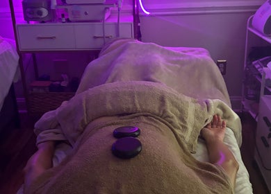 Relaxing spa treatment with hot stones at B&G Wellness Salon in Roswell, Georgia, US, under ambient purple lighting.